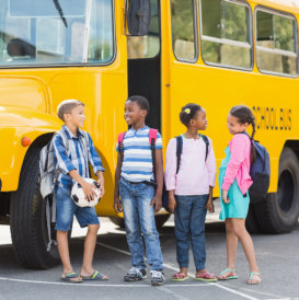 kids with backpacks standing beside the school bus
